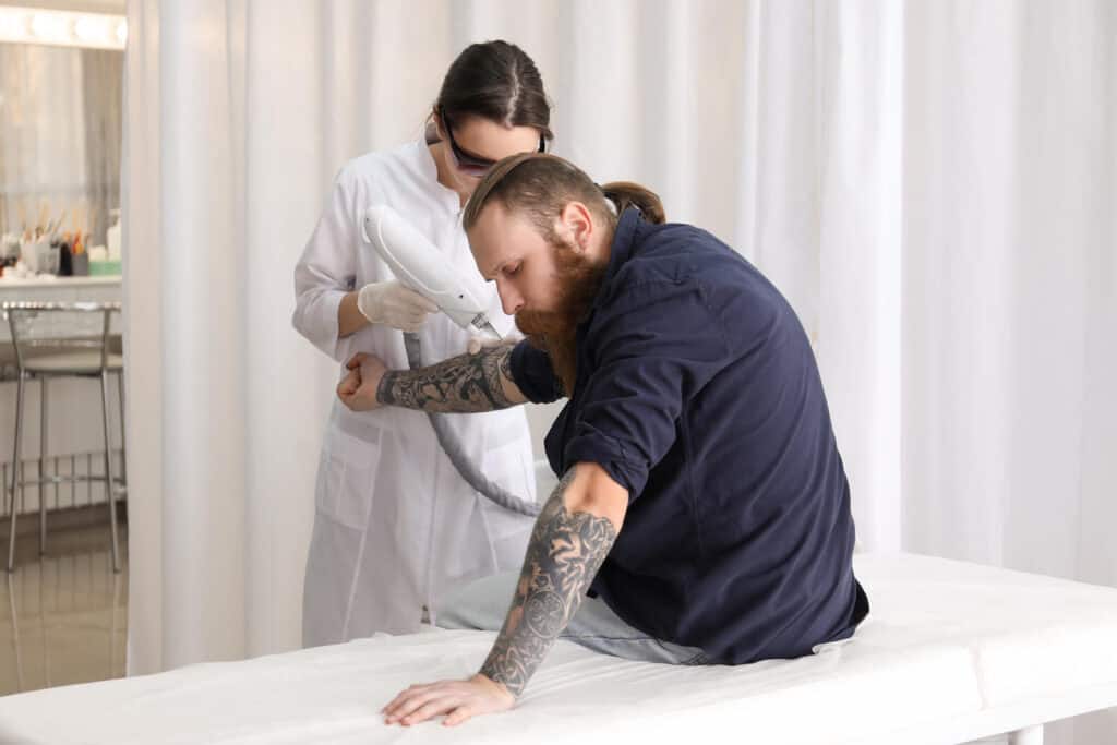 A man undergoing laser removal treatment for his arm tattoo at a specialist clinic.