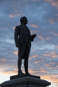 Statue of Captain James Cook against a sunset, to remember his role in tattoo trends